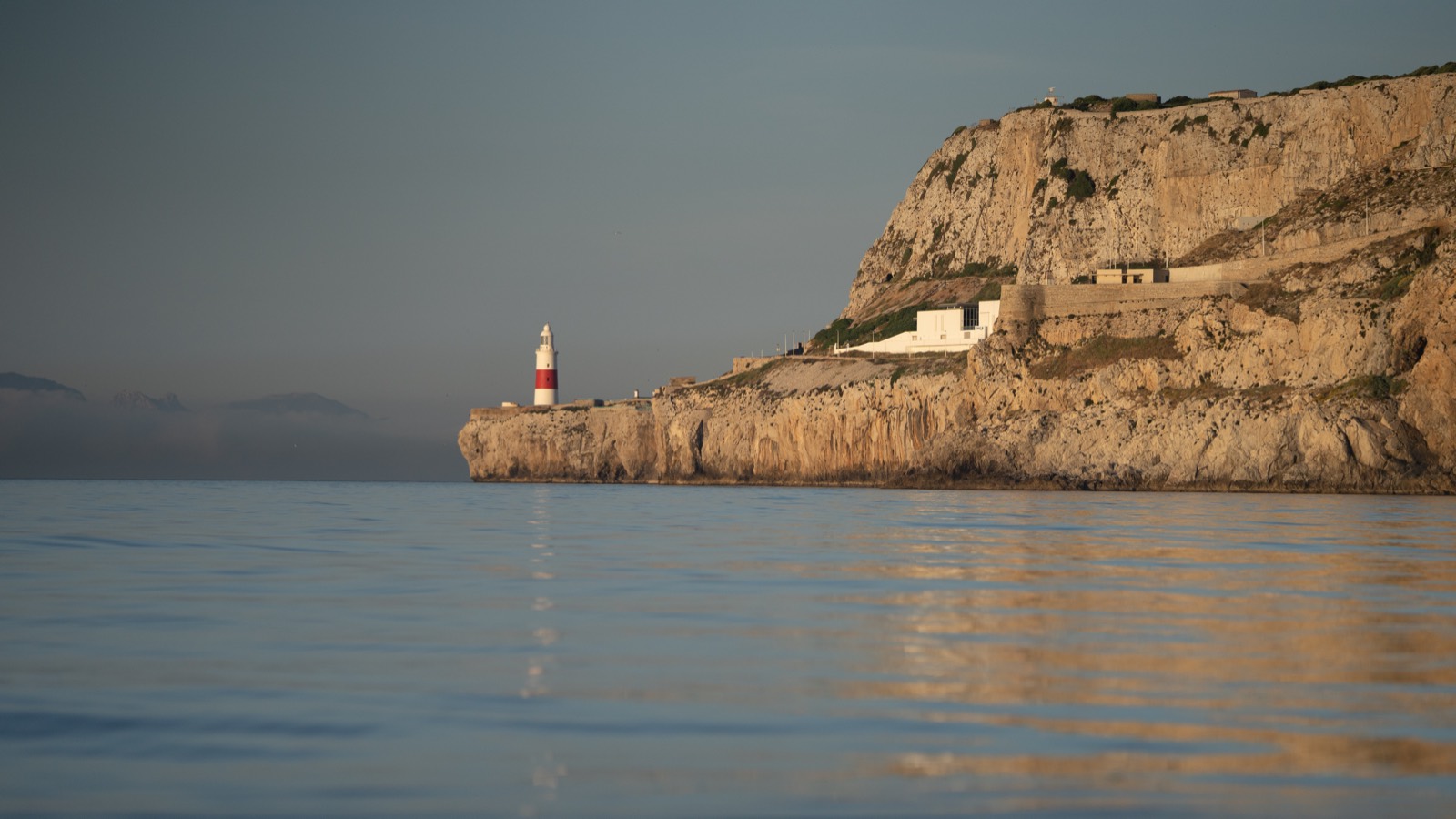 The cliffs and lighthouse at Europa Point, Gibraltar, on calm water